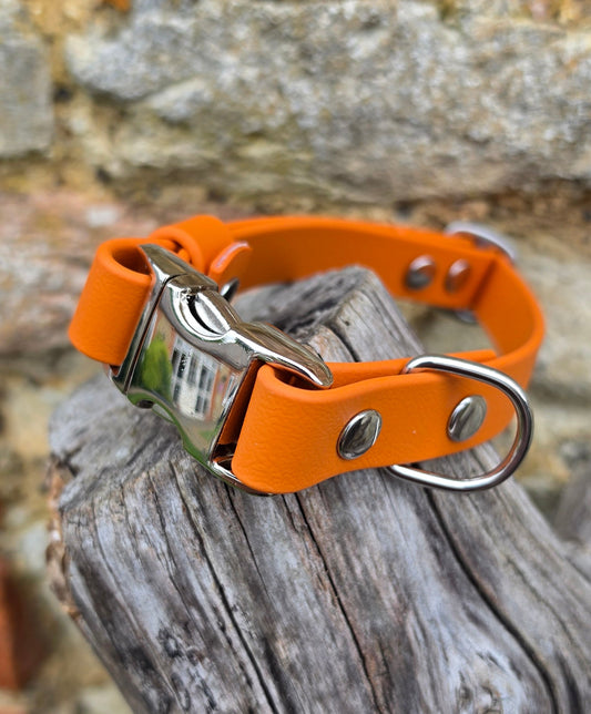 Orange leather dog collar with metal clasp on a wooden surface