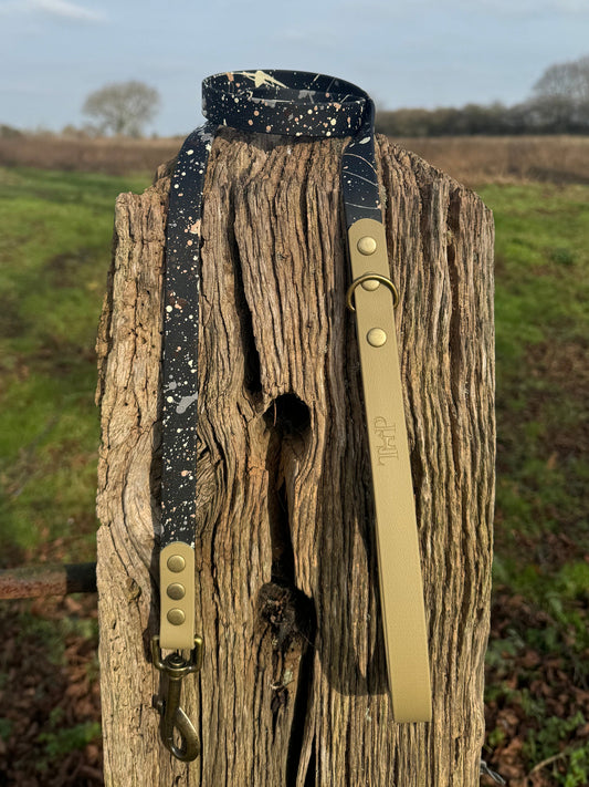 A black and brown BioThane dog collar with a terra splatter design, displayed on a wooden post.
